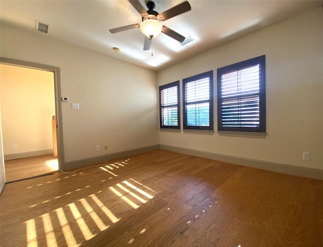 empty room featuring a ceiling fan, baseboards, and wood finished floors