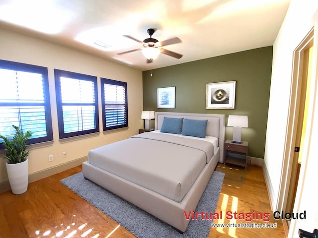 bedroom with visible vents, ceiling fan, baseboards, and wood finished floors