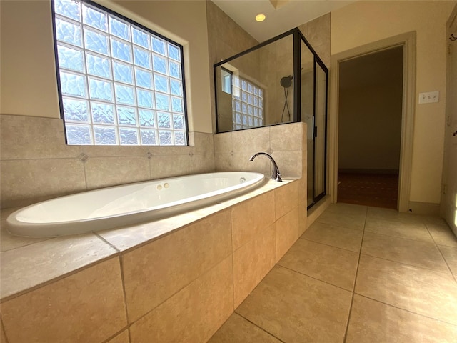 bathroom featuring a stall shower, a bath, and tile patterned floors