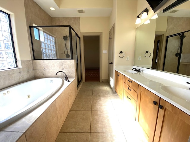 full bathroom featuring a sink, a jetted tub, a shower stall, tile patterned floors, and double vanity