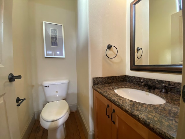 bathroom featuring toilet, wood finished floors, vanity, and baseboards