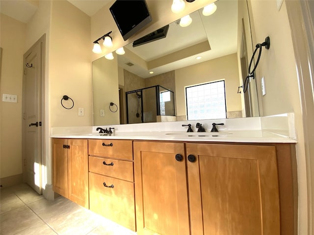 bathroom featuring double vanity, a raised ceiling, a sink, a shower stall, and tile patterned flooring