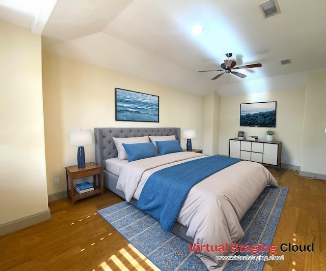 bedroom with visible vents, vaulted ceiling, baseboards, and wood finished floors