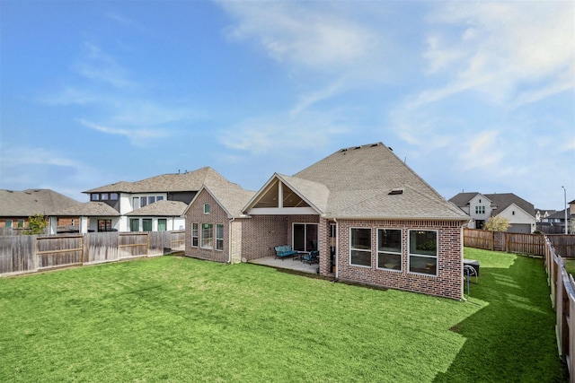 back of house with brick siding, a patio, a shingled roof, a lawn, and a fenced backyard