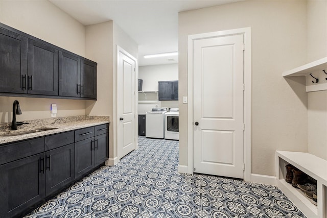 kitchen featuring baseboards, dark cabinetry, separate washer and dryer, and a sink