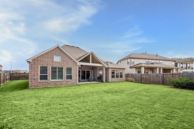 back of property with a patio area, brick siding, a lawn, and a fenced backyard