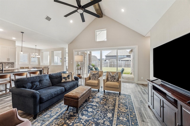 living area featuring wood finish floors, visible vents, high vaulted ceiling, beamed ceiling, and ceiling fan with notable chandelier