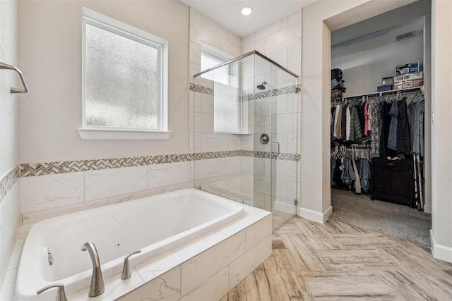 bathroom featuring a garden tub, baseboards, a walk in closet, and a shower stall