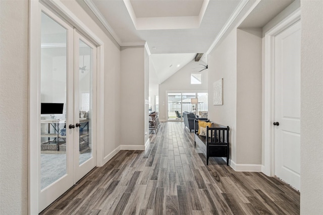 hall featuring baseboards, dark wood finished floors, lofted ceiling, crown molding, and french doors