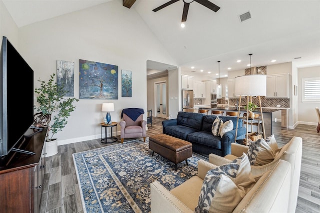 living area featuring dark wood finished floors, visible vents, a ceiling fan, high vaulted ceiling, and baseboards