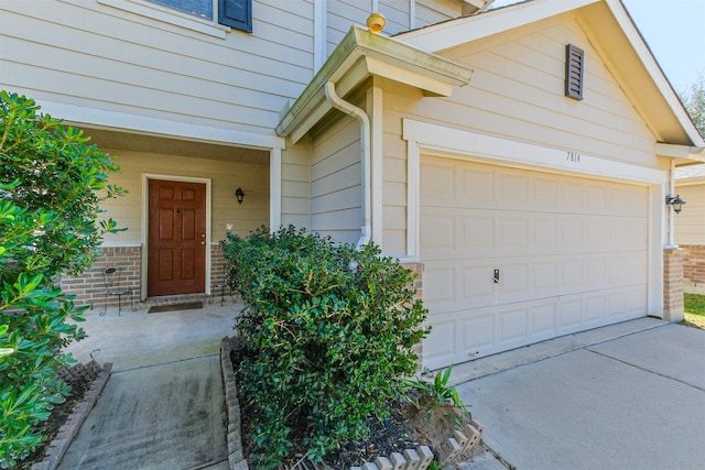 view of exterior entry featuring brick siding, concrete driveway, and an attached garage