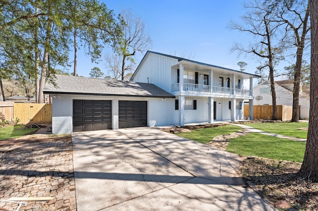 view of front of property with a balcony, driveway, an attached garage, and fence