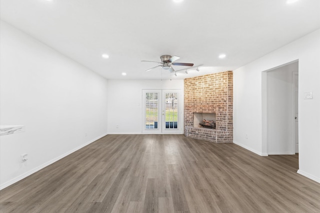 unfurnished living room featuring ceiling fan, recessed lighting, wood finished floors, baseboards, and a brick fireplace