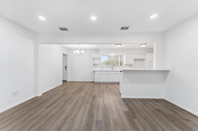 kitchen featuring a sink, visible vents, light wood-style floors, white cabinetry, and light countertops