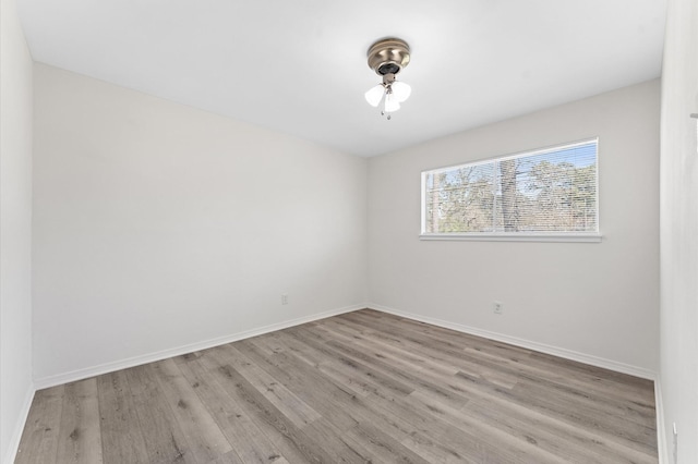 spare room with wood finished floors, a ceiling fan, and baseboards