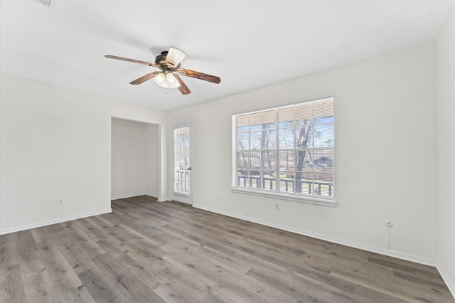 empty room featuring ceiling fan, baseboards, and wood finished floors