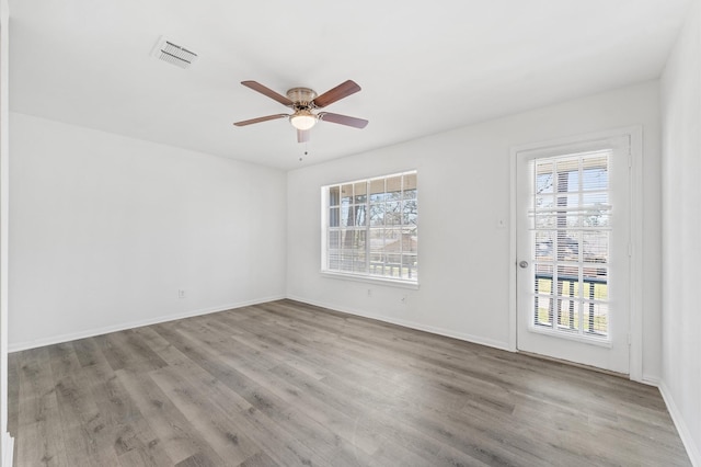 unfurnished room with baseboards, wood finished floors, visible vents, and a ceiling fan