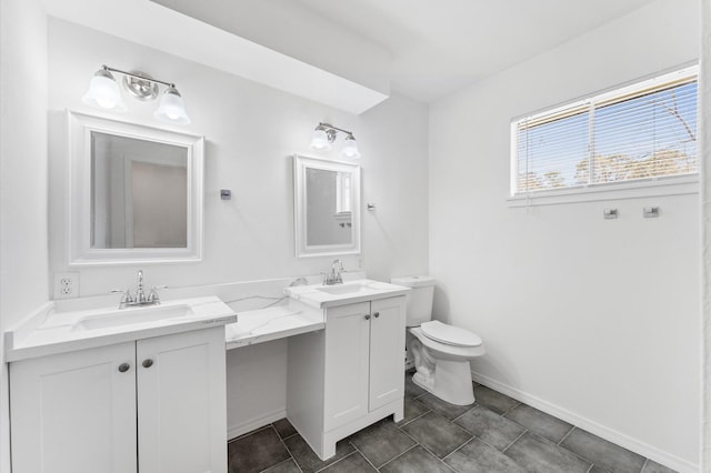 bathroom featuring double vanity, baseboards, toilet, and a sink