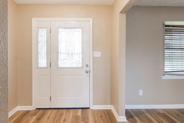 entryway featuring baseboards, a textured ceiling, and wood finished floors