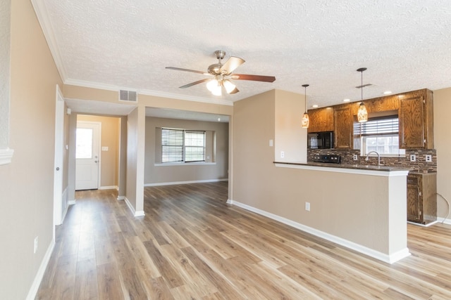 kitchen with black microwave, visible vents, light wood-style floors, brown cabinets, and tasteful backsplash