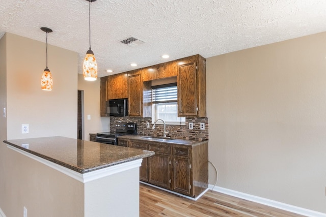 kitchen with visible vents, range with electric cooktop, a sink, black microwave, and backsplash