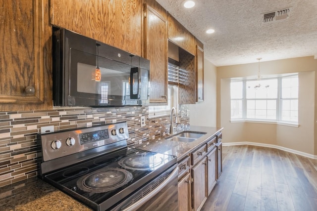 kitchen featuring black microwave, wood finished floors, a sink, visible vents, and stainless steel range with electric cooktop