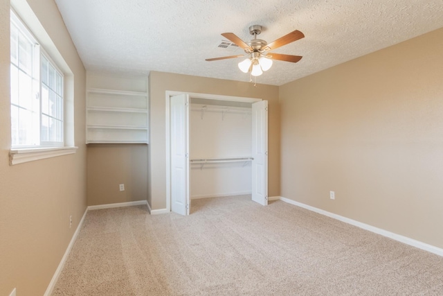 unfurnished bedroom with a closet, visible vents, carpet flooring, a textured ceiling, and baseboards