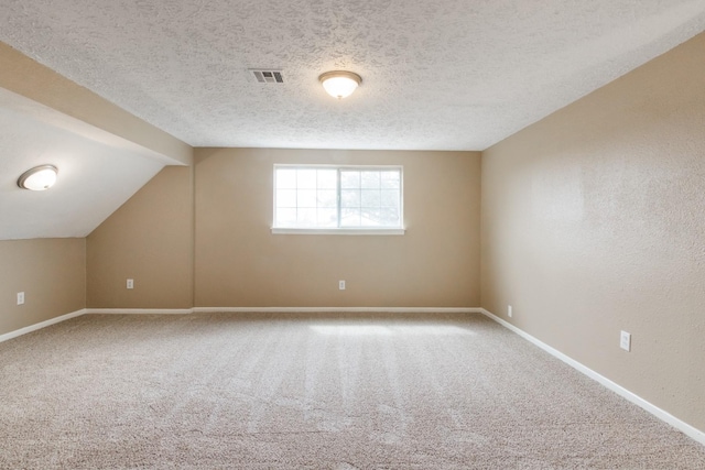 bonus room featuring carpet floors, lofted ceiling, visible vents, a textured ceiling, and baseboards