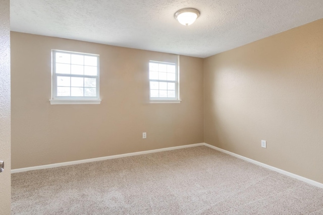 empty room with a wealth of natural light, carpet, a textured ceiling, and baseboards