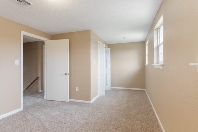 unfurnished bedroom with visible vents, carpet flooring, a textured ceiling, and baseboards