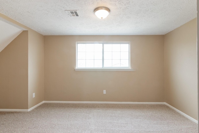 carpeted spare room featuring a textured ceiling, visible vents, and baseboards