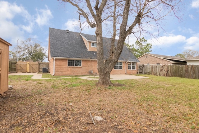 back of house featuring a patio area, brick siding, a lawn, and a fenced backyard