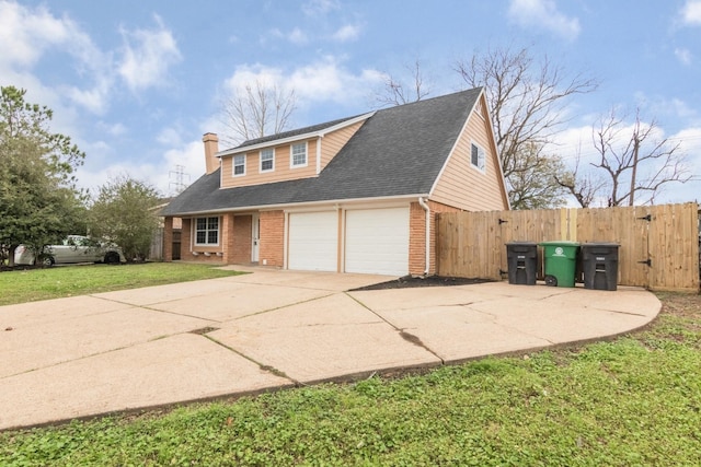 view of front of house featuring a garage, concrete driveway, a gate, a front lawn, and brick siding