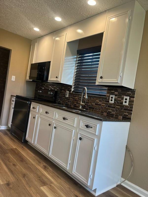 11422 Sagedowne Ln, Houston, TX 77089 - kitchen with white cabinetry, baseboards, wood finished floors, and black appliances