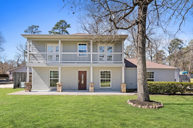 rear view of house featuring brick siding, a yard, and a balcony