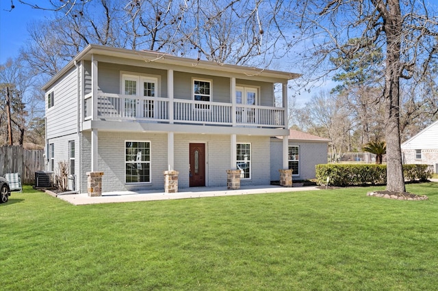 rear view of property with a balcony, a yard, central AC, and brick siding