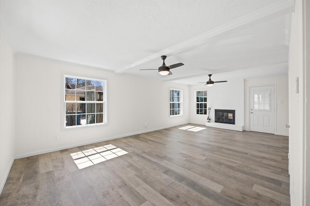 unfurnished living room with a brick fireplace, a healthy amount of sunlight, and wood finished floors