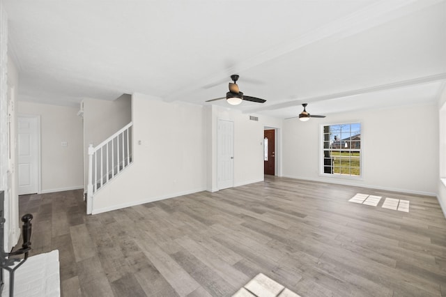 unfurnished living room with light wood-type flooring, visible vents, stairway, and baseboards