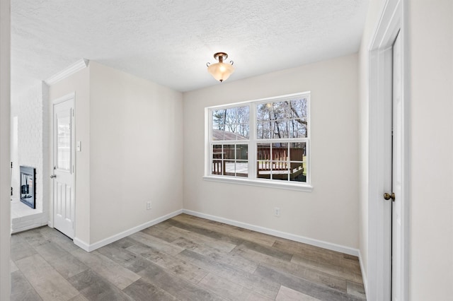 interior space with a textured ceiling, heating unit, wood finished floors, and baseboards