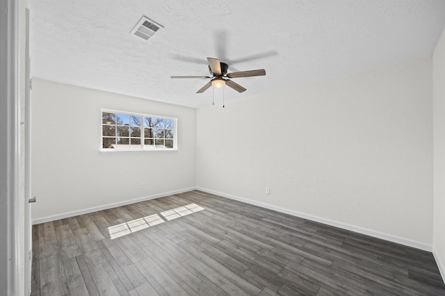 spare room featuring dark wood-style floors, visible vents, a textured ceiling, and baseboards