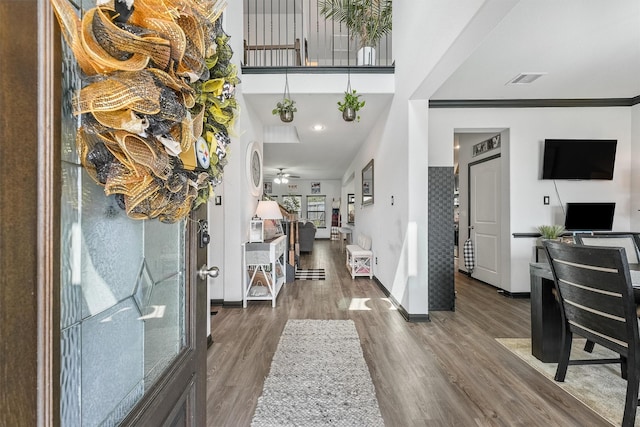 foyer entrance featuring ceiling fan, a high ceiling, wood finished floors, and baseboards