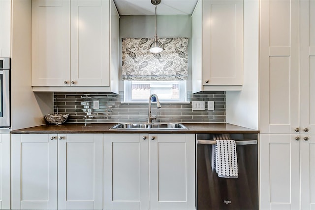 kitchen featuring dark countertops, tasteful backsplash, decorative light fixtures, stainless steel appliances, and a sink