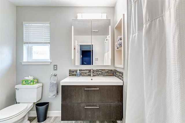 bathroom with backsplash, toilet, vanity, and baseboards