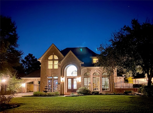 view of front of property with a gate, french doors, a lawn, and fence