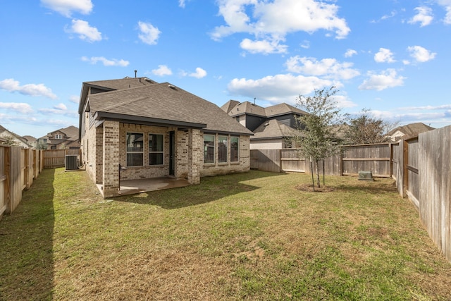 rear view of property featuring cooling unit, a fenced backyard, brick siding, a lawn, and a patio area