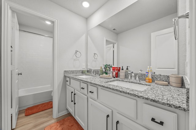 full bath with double vanity, wood finished floors, a sink, and visible vents