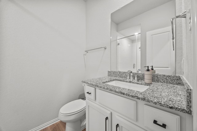 bathroom with toilet, a stall shower, wood finished floors, and vanity