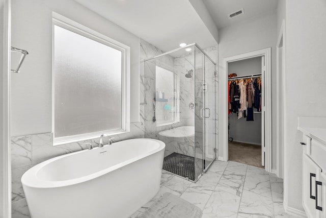 bathroom with a marble finish shower, visible vents, a soaking tub, marble finish floor, and a walk in closet