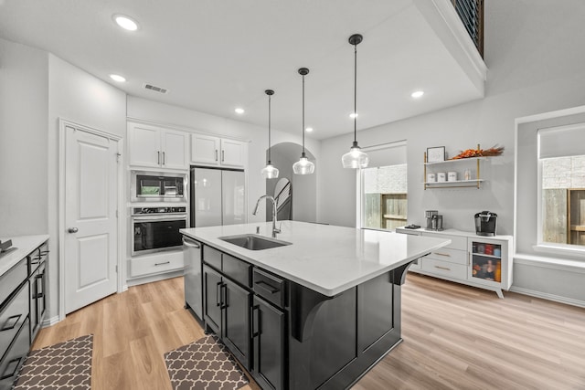 kitchen with stainless steel appliances, visible vents, light wood-style floors, white cabinets, and a sink