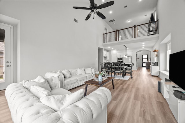 living area featuring visible vents, arched walkways, a ceiling fan, light wood-style flooring, and recessed lighting